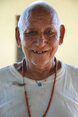Smiling elderly man with beaded necklace.